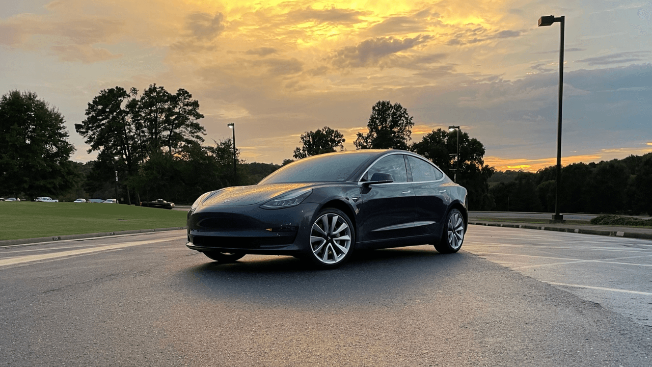 Tesla Model 3 parked underneath the sunset.